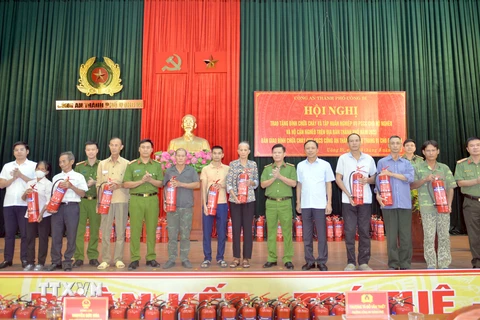Lãnh đạo thành phố và Công an Uông Bí trao tặng bình chữa cháy cho các hộ nghèo, cận nghèo. (Ảnh: Thanh Vân/TTXVN)
