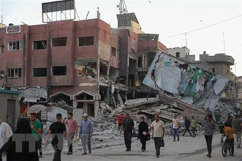 Người dân di chuyển qua những tòa nhà bị phá hủy sau các cuộc không kích của Israel tại Dải Gaza ngày 16/10. (Ảnh: THX/TTXVN) 