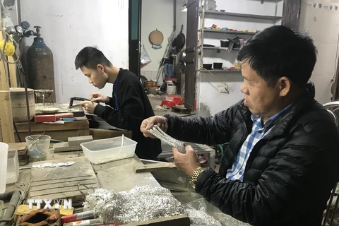 Nghệ nhân Phạm Bình Minh kiểm tra chất lượng dây truyền bạc. (Ảnh: Tiến Vĩnh/TTXVN)
