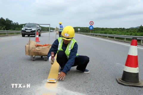 Thi công bổ sung lắp đặt các đinh phản quang giữa tim đường có hai làn xe. (Ảnh: Đỗ Trưởng/TTXVN)