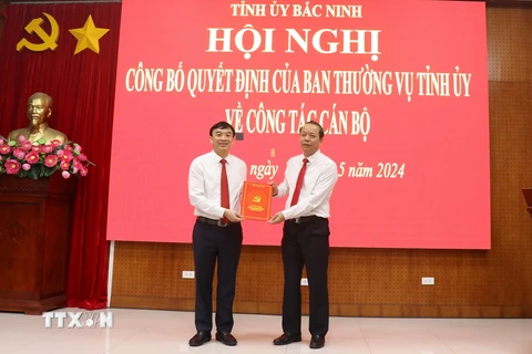 Phó Bí thư Thường trực Tỉnh ủy, Chủ tịch Hội đồng Nhân dân tỉnh Bắc Ninh Nguyễn Quốc Chung (phải) trao Quyết định của Ban Thường vụ Tỉnh ủy Bắc Ninh cho ông Nguyễn Đình Lợi. (Ảnh: Thanh Thương/TTXVN)