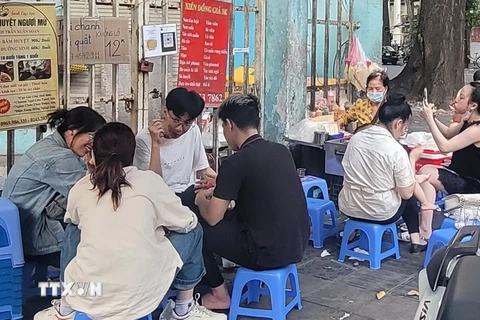 Học sinh, sinh viên hồn nhiên ngồi ăn quán xiên nướng vỉa hè quanh khu vực trường Tiểu học Lê Ngọc Hân, quận Hai Bà Trưng. (Ảnh: Phương Anh/TTXVN)