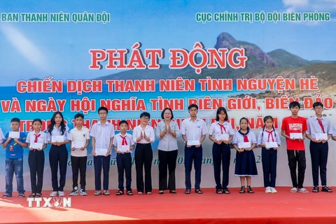 Các đại biểu tặng quà cho các cháu học sinh có hoàn cảnh khó khăn vượt khó, học giỏi. (Ảnh: Huỳnh Sơn/TTXVN)