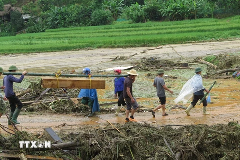 Đưa thi thể được tìm thấy sau cơn lũ dữ ở làng Nủ (Lào Cai) về an táng. (Ảnh: Hồng Ninh/TTXVN)