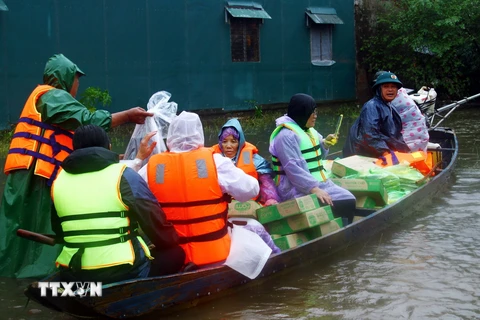 Dùng thuyền vận chuyển nhu yếu phẩm, nước sạch đến người dân các vùng thấp trũng còn bị ngập nước của huyện Lệ Thủy (Quảng Bình). (Ảnh: Tá Chuyên/TTXVN)