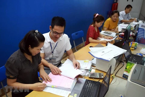 Cán bộ thuế tỉnh Thái Nguyên hướng dẫn doanh nghiệp Công ty Thép Việt Cường khai báo thủ tục giãn thuế. (Ảnh: Danh Lam/TTXVN)