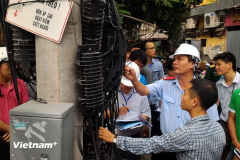 Trưởng đoàn thanh tra Nguyễn Văn Minh (đội mũ) kiểm tra sai sót của doanh nghiệp trong quá trình lắp đặt đường dây, cáp đi nổi. (Ảnh: T.H/Vietnam+)