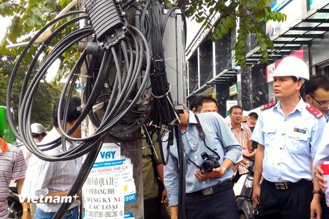 Chánh thanh tra Nguyễn Văn Minh (đội mũ) kiểm tra việc chấp hành quy định về cáp viễn thông tại phố Thái Hà. (Ảnh: T.H/Vietnam+)