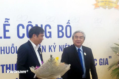 Bộ trưởng Nguyễn Quân (phải) tặng hoa chúc mừng diễn đàn. (Ảnh: T.H/Vietnam+)