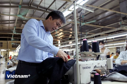 Phó Bí thư Lê Văn Huân kiểm tra sản phẩm tại nhà máy Sung Woo Vina. (Ảnh: PV/Vietnam+)