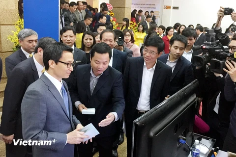 Nhân viên bưu điện trình bày về dịch vụ mới với Phó Thủ tướng Vũ Đức Đam. (Ảnh: T.H/Vietnam+)