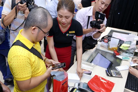 Nhiều người đến FPT Shop từ rất sớm để sở hữu iPhone mới chính hãng. (Ảnh: CTV/Vietnam+)