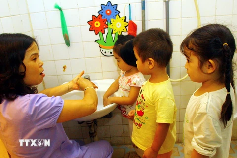 Hướng dẫn cho các cháu 3 tuổi rửa tay bằng xà phòng tại trường Mẫu giáo Tương Mai. (Ảnh: Bích Ngọc/TTXVN)