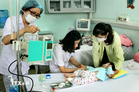 Nhân viên y tế chăm sóc cho trẻ bị rối loạn tiêu hóa. (Ảnh: TTXVN/Vietnam+)