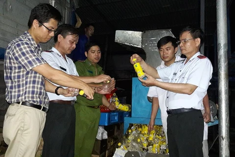 Đoàn thanh tra cùng đại diện Công ty URC Hà Nội giám sát việc tiêu hủy hàng không đạt chất lượng. (Ảnh: BYT cung cấp)