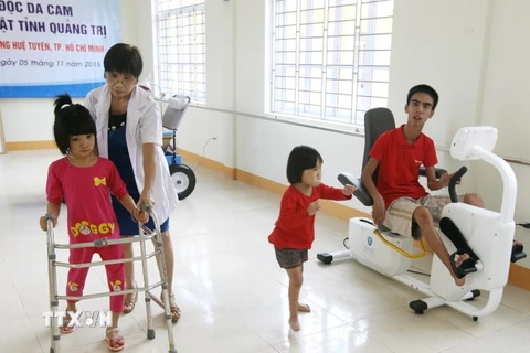 Nhân viên y tế giúp đỡ bệnh nhân nhi vận động để phục hồi chức năng. (Ảnh: TTXVN/Vietnam+)
