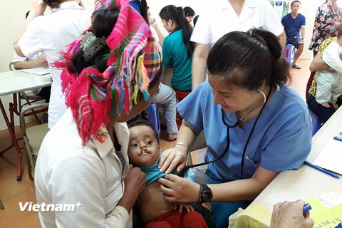 Nhân viên y tế khám cho trẻ bị dị tật môi tại Bệnh viện Hữu nghị Việt Nam-Cuba. (Ảnh: PV/Vietnam+)