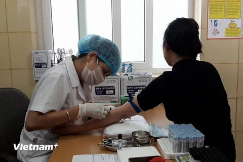 Nhân viên y tế lẫy máu xét nghiệm cho bệnh nhân tại Bệnh viện K. (Ảnh: PV/Vietnam+)