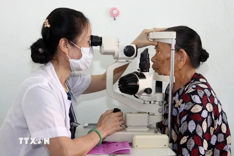 Nhân viên y tế khám mắt cho người dân. (Ảnh: TTXVN/Vietnam+)