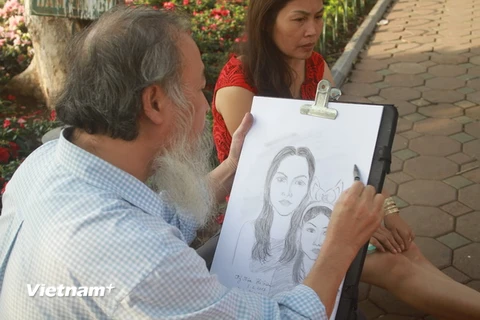Người họa sỹ già chăm chút cho tác phẩm của mình. (Ảnh: Khánh Ly/Vietnam+)