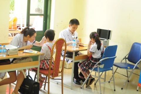 Bác sỹ khám mắt cho học sinh. (Ảnh: TTXVN/Vietnam+)