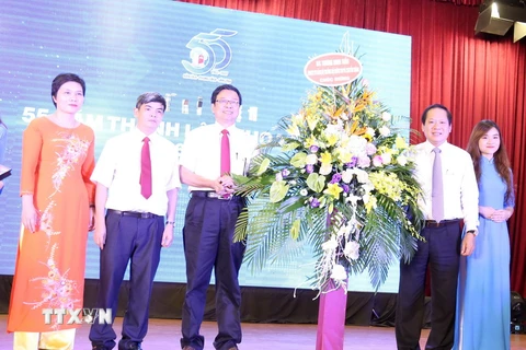 Ông Trương Minh Tuấn, Ủy viên Trung ương Đảng, Bộ trưởng Bộ Thông tin và Truyền thông tặng hoa chúc mừng Khoa Báo chí. (Ảnh: Anh Linh/TTXVN phát)