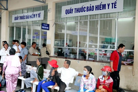 Người dân chờ xếp hàng mua thuốc. (Ảnh: TTXVN/Vietnam+)