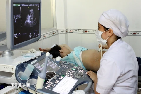 Nhân viên y tế siêu âm sàng lọc dị tật bẩm sinh cho thai phụ. (Ảnh: Dương Ngọc/TTXVN)