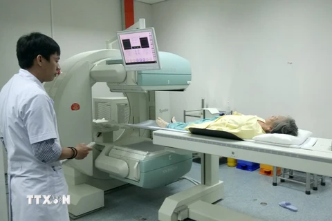 Bệnh nhân ung thư sau khi tiêm thuốc phóng xạ được đưa vào máy Spect để kiểm tra di căn ung thư xương. (Ảnh: TTXVN)