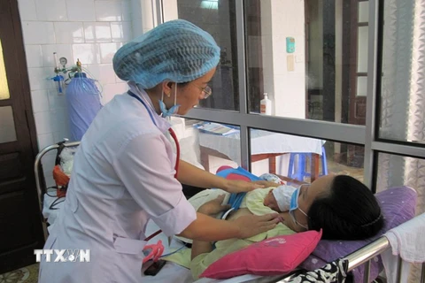 Bác sỹ thăm khám cho mẹ con sản phụ mới sinh. (Ảnh: TTXVN)