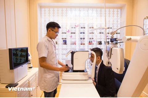 Chuyên viên khúc xạ kiểm tra thị lực cho khách hàng bằng máy đo khúc xạ. (Ảnh: PV/Vietnam+)