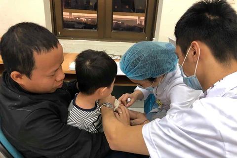 Bác sỹ lấy máu xét nghiệm cho trẻ. (Ảnh: PV/Vietnam+)