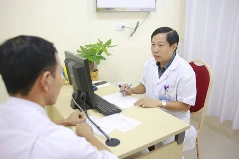 Phó giáo sư Nguyễn Quang khám cho một bệnh nhân. (Ảnh: PV/Vietnam+)