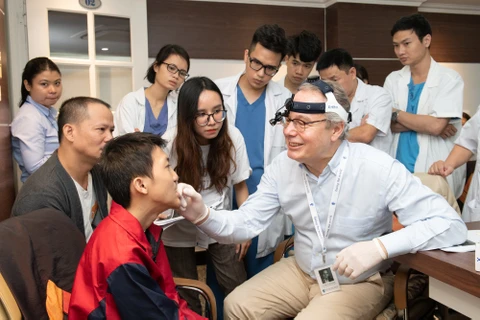 Bác sỹ của tổ chức Facing the World khám cho bệnh nhân bị dị tật. (Ảnh: PV/Vietnam+)