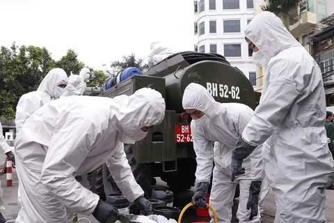 Lực lượng hóa học pha hóa chất để tiến hành phun tiêu tẩy khu vực phố Trúc Bạch, quận Ba Đình. (Ảnh: Dương Giang/TTXVN)