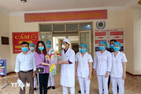 Một bệnh nhân được chữa khỏi bệnh COVID-19 tại Bệnh viện đa khoa khu vực Cửa khẩu Quốc tế Cầu Treo tặng hoa tri ân đội ngũ y bác sỹ. (Ảnh: TTXVN phát)