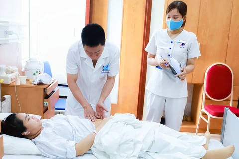 Bác sỹ khám, chăm sóc sức khỏe cho thai phụ. (Ảnh: PV/Vietnam+)