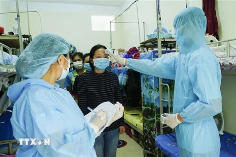 Nhân viên y tế đo thân nhiệt và kiểm tra sức khỏe cho các lưu học sinh Lào. (Ảnh: Xuân Tư/TTXVN)