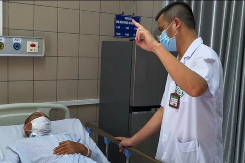 Bác sỹ Nguyên kiểm tra thị lực của bệnh nhân ngộ độc methanol. (Ảnh: PV/Vietnam+)