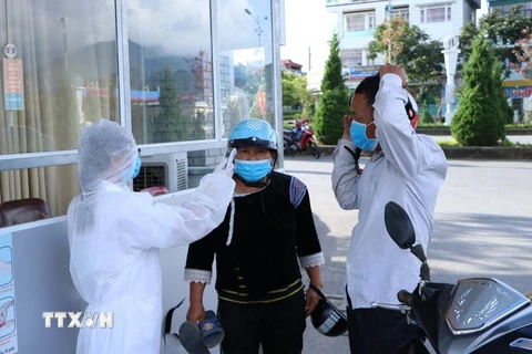 Cán bộ nhân viên y tế của Bệnh viện Đa khoa tỉnh Lai Châu kiểm soát đo thân nhiệt cho người dân trước khi vào thăm, khám bệnh. (Ảnh: PV)