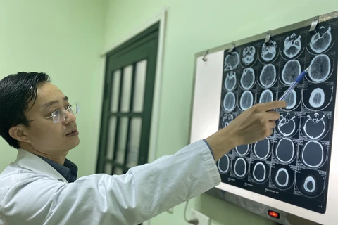 Tiến sỹ Bùi Huy Mạnh xem phim chụp của bệnh nhân. (Ảnh: PV/Vietnam+)