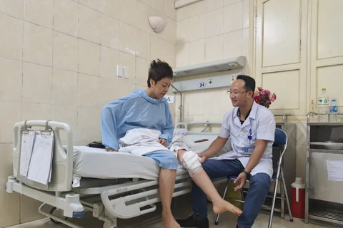 Bác sỹ khám cho nữ huấn luyện viên bắn súng Nguyễn Thị Nhung sau phẫu thuật. (Ảnh: PV/Vietnam+)