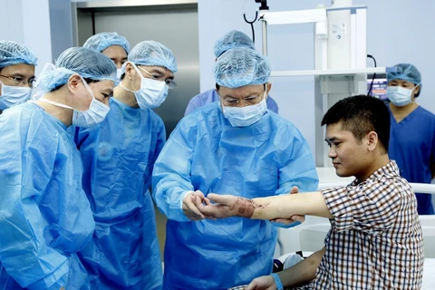 Các y bác sỹ Bệnh viện Trung ương Quân đội 108 kiểm tra tay cho bệnh nhân Vương sau khi ghép. (Ảnh: PV/Vietnam+)