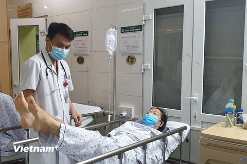 Một bệnh nhân bị đột quỵ đang được y bác sỹ thực hiện phục hồi chức năng ngay trên giường bệnh. (Ảnh: T.G/Vietnam+)