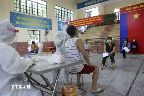 Nhân viên Trung tâm y tế quận Đống Đa lấy mẫu xét nghiệm COVID-19 cho các cư dân từng đến Đà Nẵng từ ngày 1-14/5. (Ảnh: Tuấn Đức/TTXVN)