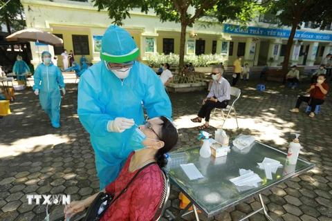 Nhân viên y tế lấy mẫu xét nghiệm cho người dân phường Nghĩa Đô. (Ảnh: Vũ Sinh/TTXVN)