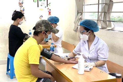 Nhân viên y tế khám sức khỏe cho người dân trước khi tiêm chủng. (Ảnh: TTXVN/Vietnam+)