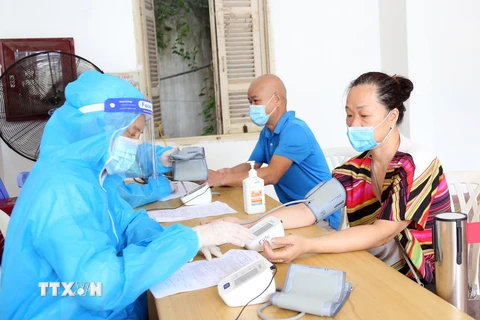 Nhân viên y tế đo huyết áp cho người dân. (Ảnh: TTXVN/Vietnam+)