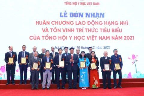 Thứ trưởng Bộ Y tế Đỗ Xuân Tuyên trao biểu trưng tôn vinh các tri thức tiêu biểu của Tổng hội Y học Việt Nam. (Ảnh: Văn Điệp/TTXVN)