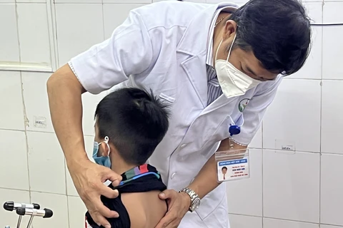 Bé trai bị gù vẹo cột sống được bác sỹ thăm khám. (Ảnh: PV/Vietnam+)